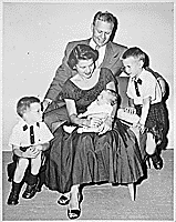 H0006-1. Mrs. Ford holds Steven Ford as Gerald R. Ford, Jr., Jack Ford, and Michael Ford look on. June 1956.