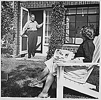 H0010-2. Gerald R. Ford stands in the doorway of their apartment at 1521 Mount Eagle Place, Alexandria, VA as Betty Ford reads a newspaper in the yard. 1952.