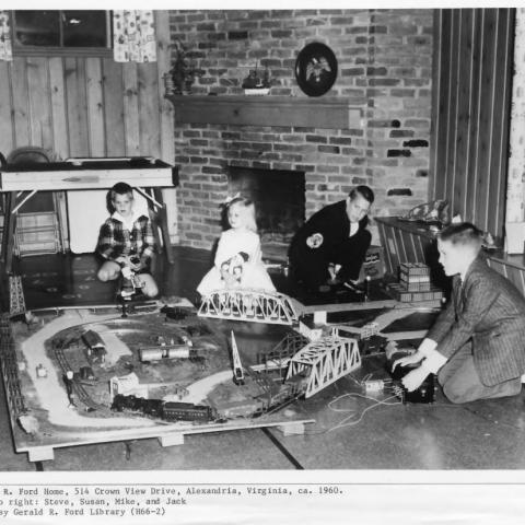 A black and white picture of the four Ford children playing on the ground with trains at their home in Alexandria, Virginia