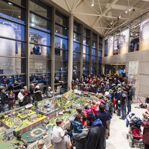 People gather around a model train set in the lobby of the Museum