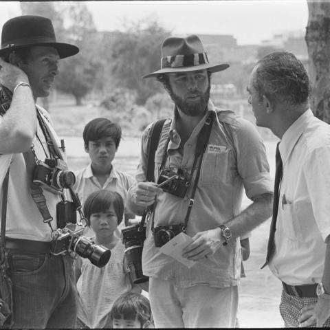 Photographer David Kennerly stands and talks to two men while three children look on.