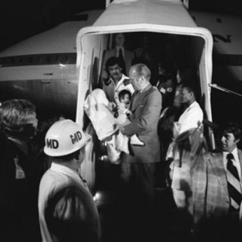 A3860-28A. President Ford carries a Vietnamese baby from “Clipper 1742," one of the Operation Babylift planes that transported approximately 325 South Vietnamese orphans from Saigon to the United States.  San Francisco International Airport. April 5, 1975.