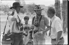 Photographer David Kennerly stands and talks to two men while three children look on.