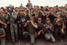 A large group of US Air Force service members are gathered, holding cameras