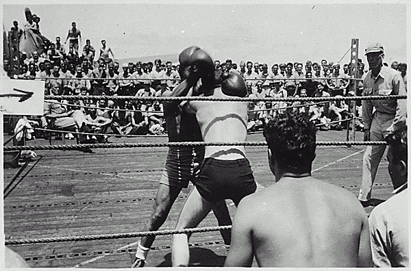 H0059-4. Lieutenant Commander Gerald R. Ford, Jr. watches a boxing match on the flight deck of the USS MONTEREY. Mr. Ford was the ship's athletic director. 1944.