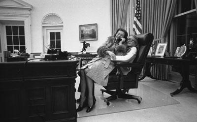 A2347-03A. First Lady Betty Ford and daughter Susan share the President's chair in the Oval Office. December 8, 1974.