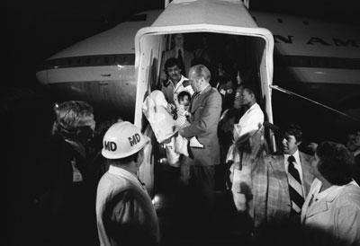 A3860-28A. President Ford carries a Vietnamese baby from “Clipper 1742," one of the Operation Babylift planes that transported approximately 325 South Vietnamese orphans from Saigon to the United States.  San Francisco International Airport. April 5, 1975.