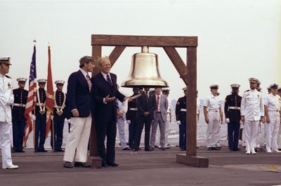 B0493-15 - President Ford initiates the ringing of Bicentennial bells across the nation while on the flight deck of the USS Forrestal with Bicentennial Administration head John Warner in observance of Operation Sail activities in New York Harbor. July 4, 1976.