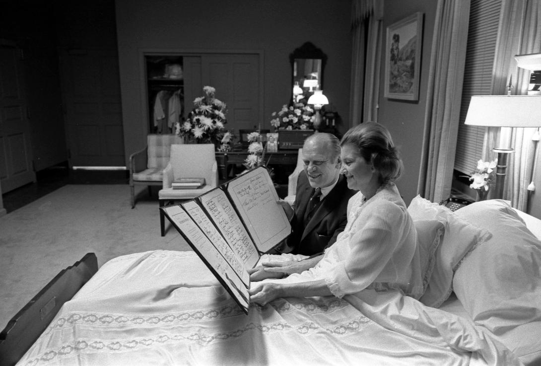 A1170-18A President and Mrs. Ford read a petition, signed by all 100 members of the United States Senate, in the President's Suite at Bethesda Naval Hospital, Bethesda, MD, following the First Lady's breast cancer surgery. October 2, 1974.