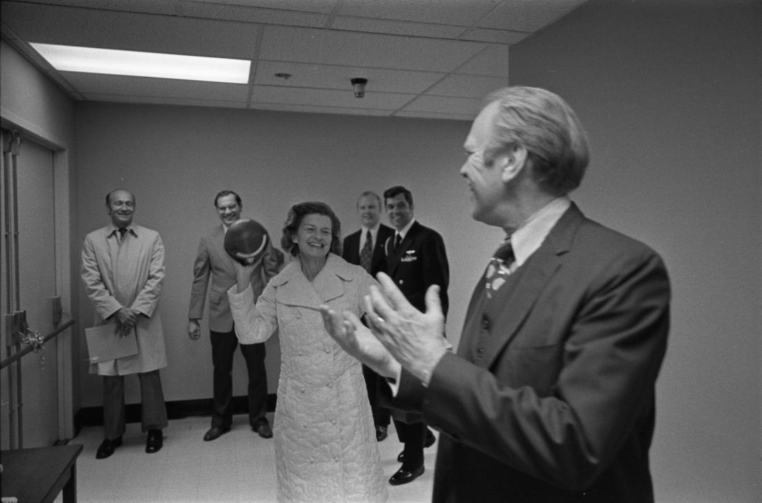 A1201-21A. President and Mrs. Ford toss a football, a gift from Washington Redskins Coach George Allen, in the hallway near the Presidential Suite at the Bethesda Naval Hospital, Bethesda, MD, following the First Lady’s breast cancer surgery. October 4, 1974.