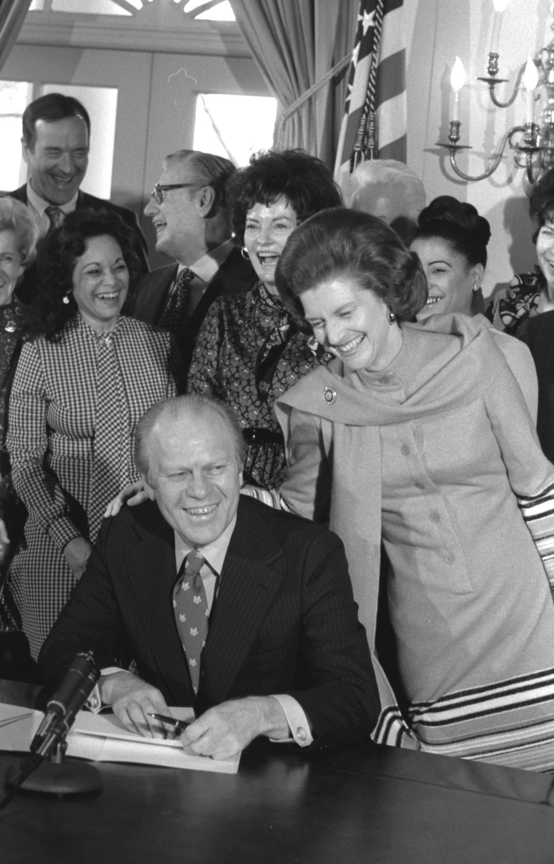 A2723-18A. First Lady Betty Ford congratulates President Gerald Ford upon his signing of an executive order establishing a National Commission on the Observance of International Women's Year.  January 9, 1975