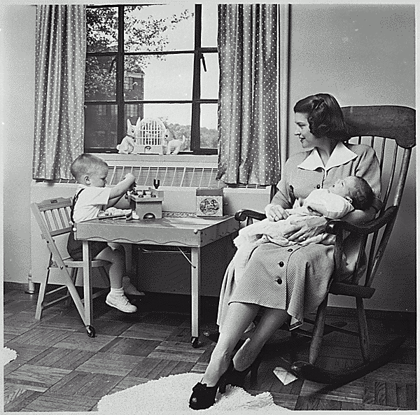 H0010-1. Betty Ford holds infant Jack Ford in her arms while Michael Ford plays at a small table in their apartment at 1521 Mount Eagle Place, Alexandria, VA. 1952.