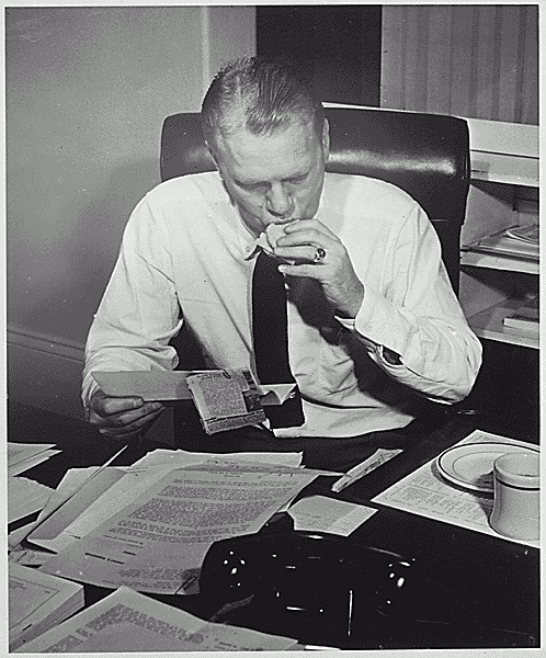 H0011-4. Representative Gerald R. Ford, Jr., reads constituent mail while eating a sandwich at his desk in his House office. 1953.