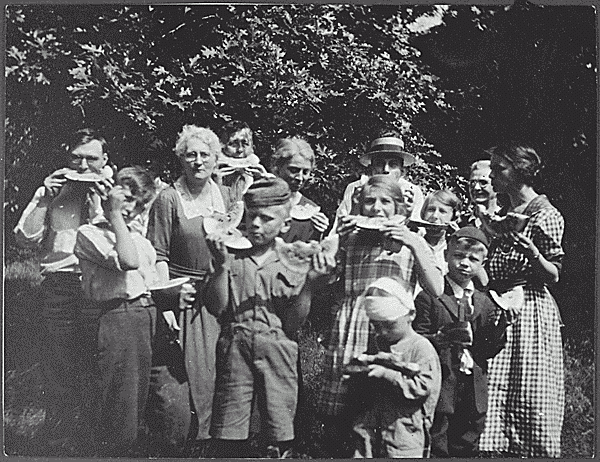 H0030-1. Gerald R. Ford, Jr., his half-brother Tom Ford, and many others enjoy some watermelon at a gathering in Oak Park, IL. 1922. Pictured are Mr. Eliker, Gardner James, Mrs. Noble, Jerry Ford, Mrs. Galaty, P.C. Galaty, Adele James, Tom Ford, Helen Galaty, Grandma James, and Mrs. Eliker (Tata).